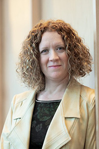 Photo of Heather Berringer — women with shoulder-length, curly hair wearing a yellow blazer. 