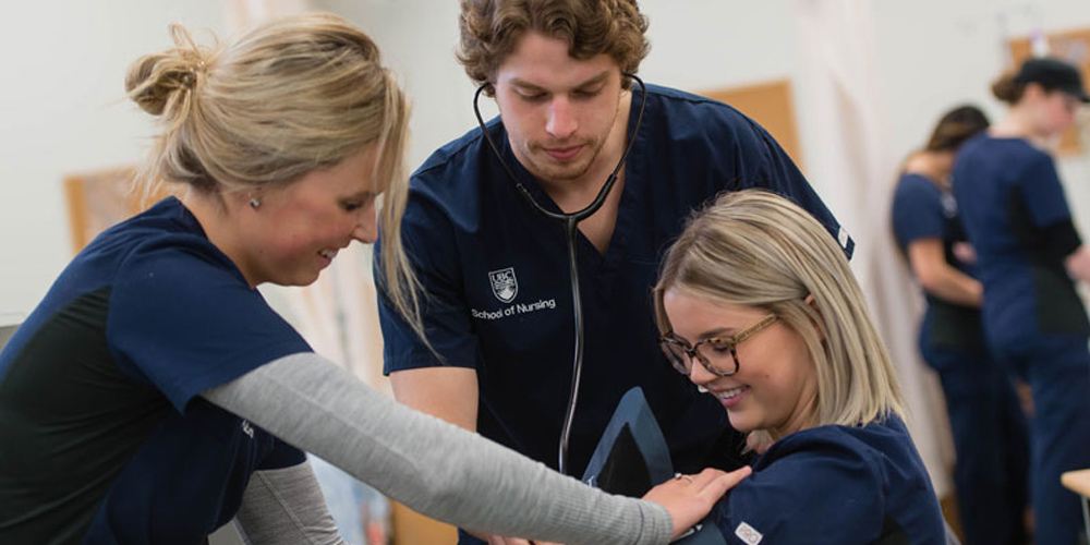Nursing students look at young woman who is getting their blood pressure checked